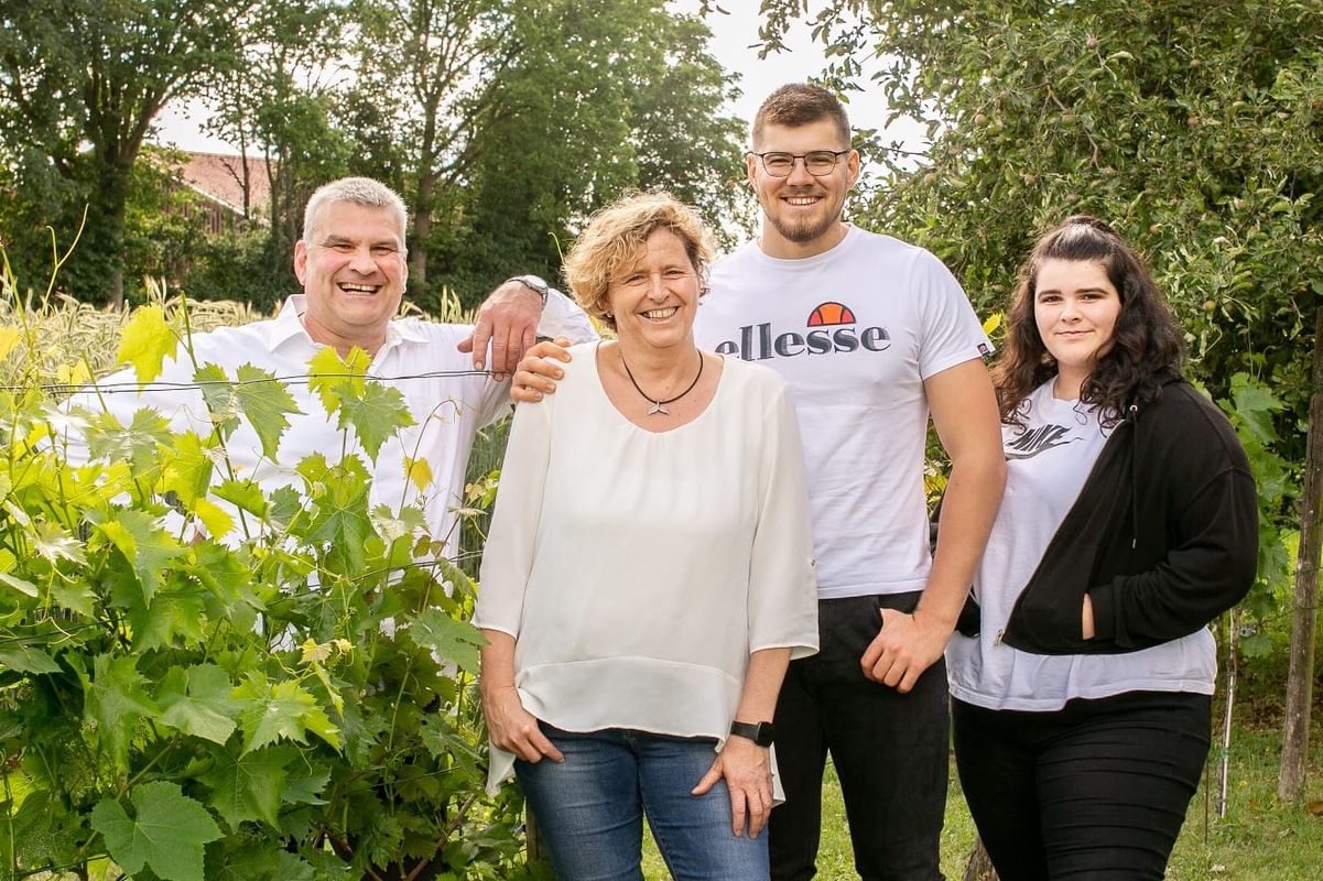 Die Familie, die im Garten steht und lächelt